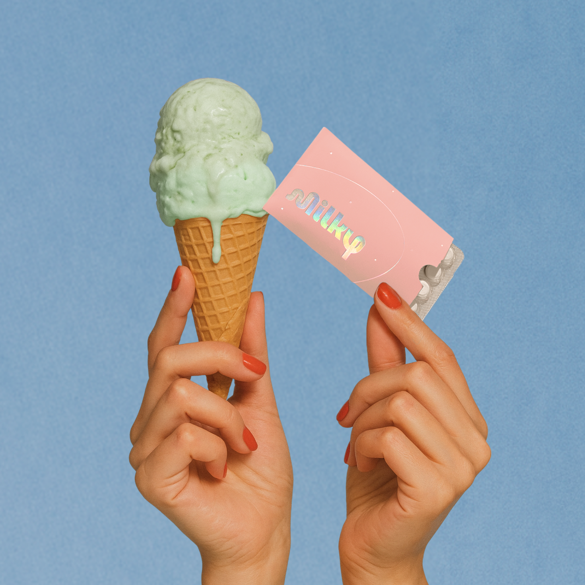 Ice cream cone and pink card held by hands against a blue background